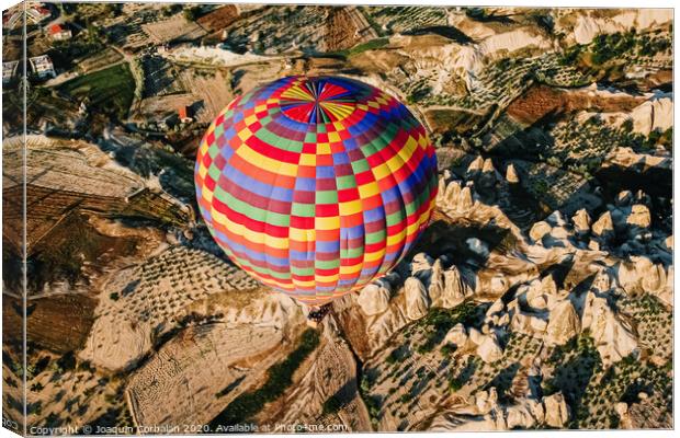 Travelers and tourists flying over mountains at sunset in a colorful aerostat balloon in Goreme, the Turkish cappadocia. Canvas Print by Joaquin Corbalan