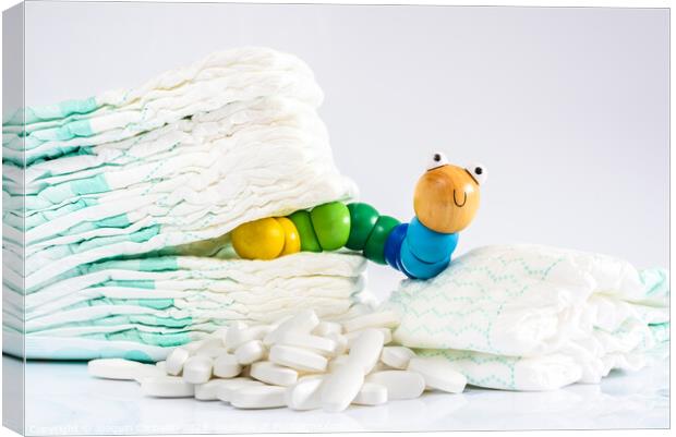 Enterobiasis is a infections of worms, Enterobius vermicularis or pinworms, which affects children and babies. A toy worm with some diapers and pills. Canvas Print by Joaquin Corbalan