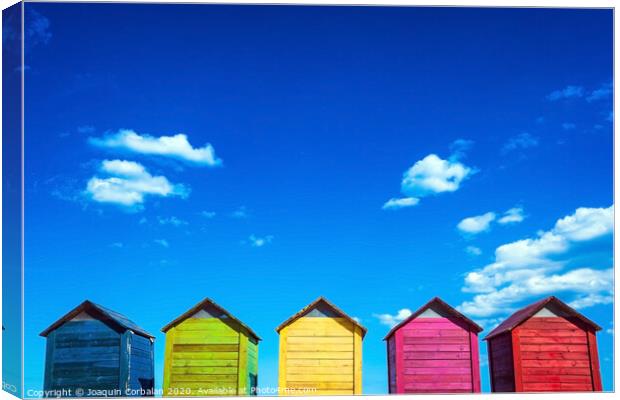 Colorful wooden changing huts on a beach, with nice background of clear blue sky on the coast. Canvas Print by Joaquin Corbalan