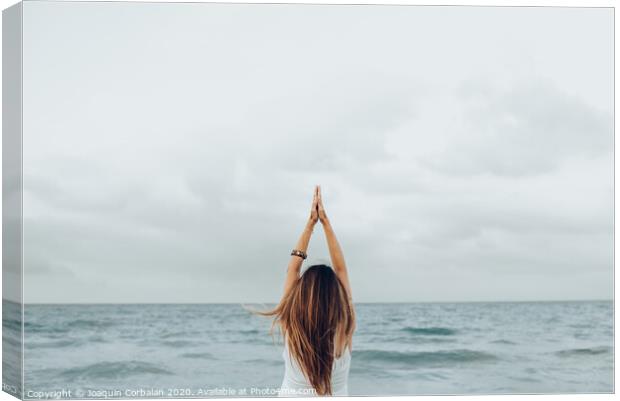 A woman relaxes in front of the sea with her hands up, unfocused background. Canvas Print by Joaquin Corbalan