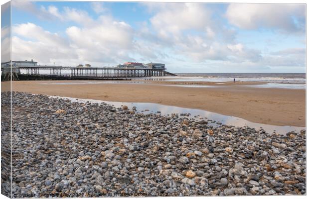 View across a sand and shingle beach with a distant pier in the background Canvas Print by Chris Yaxley