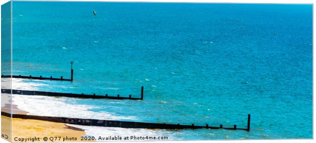 Dock pilings on a sandy beach, blue ocean and yell Canvas Print by Q77 photo