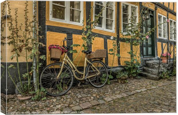 yellow bike leaning against a yellow half-timbered Canvas Print by Stig Alenäs