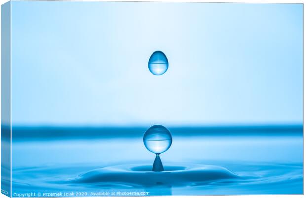Water drop splashing into blue water surface Canvas Print by Przemek Iciak