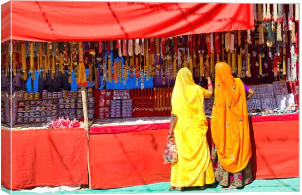 Couple of unidentified women in traditional hindu wear saree buying or shopping jewelery items in the commercial street of Pushkar fair in state of Rajasthan, India. Colorful Indian culture concept Canvas Print by Arpan Bhatia