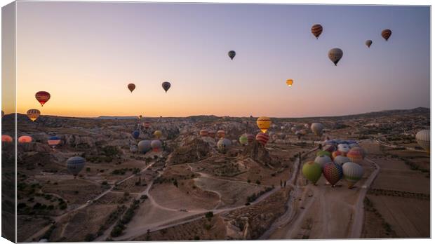 Cappadocia, Turkey - September 14, 2021: Wide angle aerial panoramic shot of colorful hot air balloons together floating in the sky at early morning sunrise horizon in Goreme national park Canvas Print by Arpan Bhatia