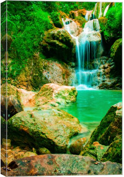 A waterfall flowing over rocks into a lake. Canvas Print by Hanif Setiawan
