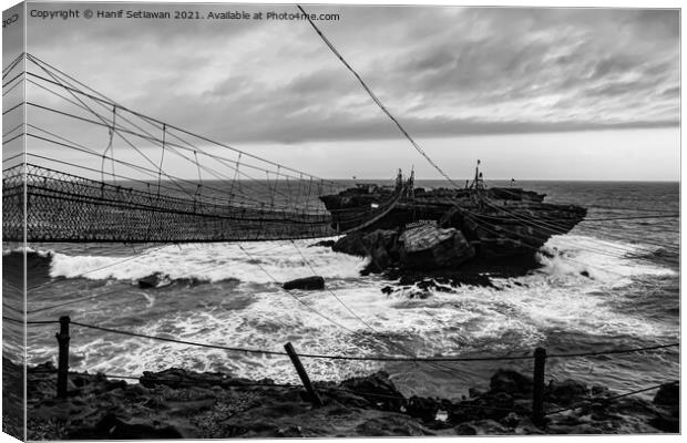 Swinging rope foot bridge to a rock island Canvas Print by Hanif Setiawan