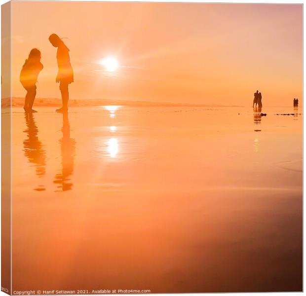 Silhouetted people in a row on sand beach Squared Canvas Print by Hanif Setiawan
