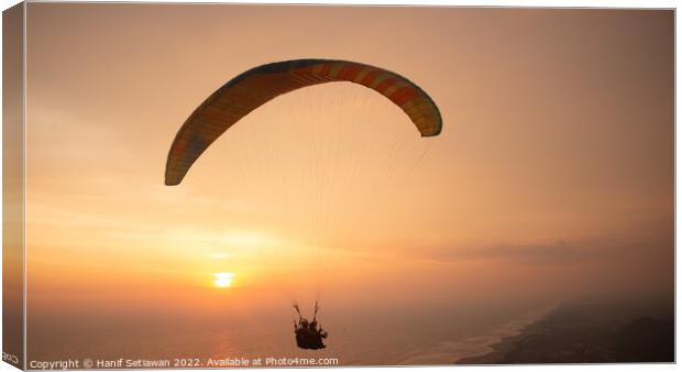 Tandem paragliding over sea and beach while golden Canvas Print by Hanif Setiawan