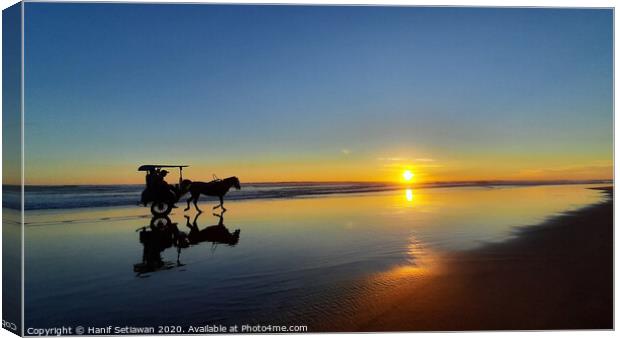 Silhouetted horse-drawn carriage beach sunset 1 Canvas Print by Hanif Setiawan