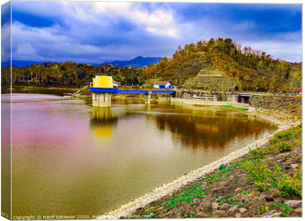 Water reservoir lake with hill, house and blue sky Canvas Print by Hanif Setiawan