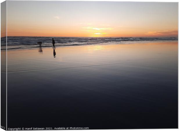 Silhouetted couple enjoys sunset at beach 3 Canvas Print by Hanif Setiawan