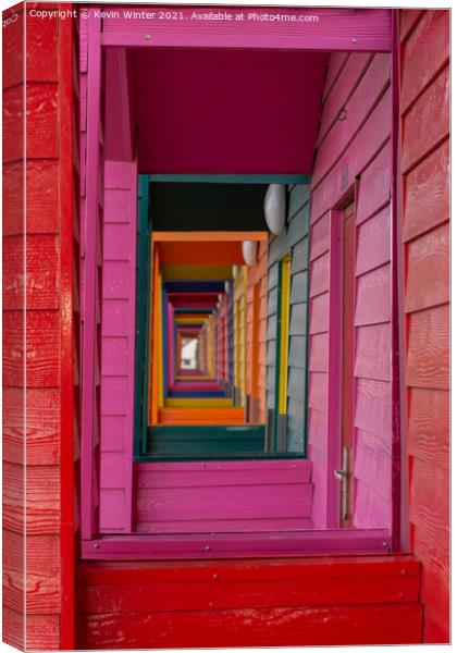 Through the beach huts Canvas Print by Kevin Winter