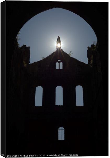 Sun flares through opening in the peak of a ruined wall of kirkstall abbey Canvas Print by Rhys Leonard