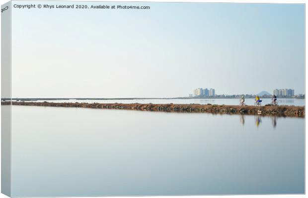Reflections of 3 pedal bike riders shimmering over a lagoon near san pedro del pinatar in spain. Canvas Print by Rhys Leonard