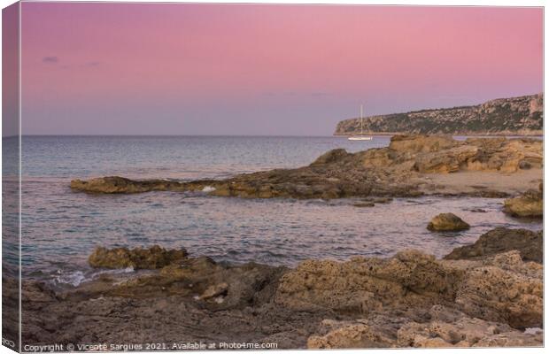 Sunset on the rocky coast with anchored sailboat Canvas Print by Vicente Sargues