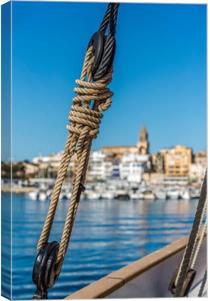 Small Spanish town in Costa Brava, Palamos.Foreground a sail boat rigging. Canvas Print by Arpad Radoczy