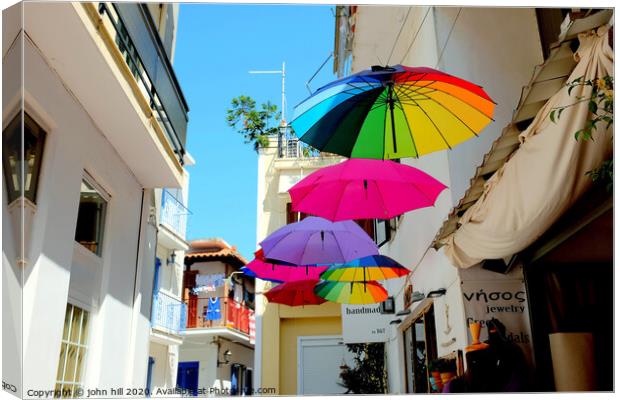 Colorful Parasols hanging in street at Skiathos Town in Greece.  Canvas Print by john hill