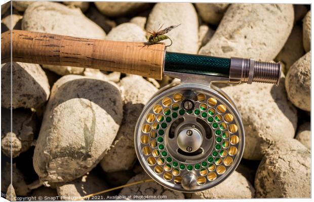A close up of a trout fly rod, reel and line on rocks, with a cicada fly Canvas Print by SnapT Photography