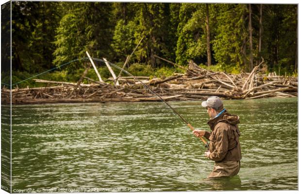 A man hooked into a fish while fly fishing on a deep green river. Canvas Print by SnapT Photography