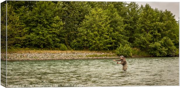 A fly fisherman spey casting while wading in a fast flowing, green, glacial river. Canvas Print by SnapT Photography