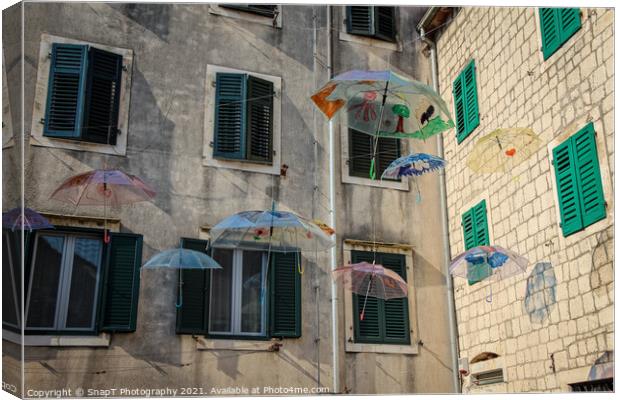 Flying umbrellas in a square in the old town of Kotor, in Montenegro Canvas Print by SnapT Photography
