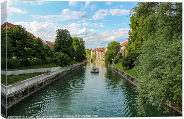 A tourist boat travelling along the Ljublijanica River in afternoon in Ljubljana Canvas Print by SnapT Photography