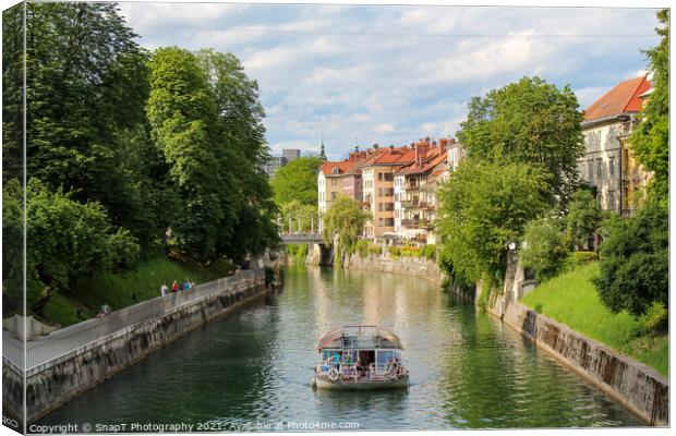 A tourist boat travelling along the Ljublijanica River in afternoon in Ljubljana Canvas Print by SnapT Photography