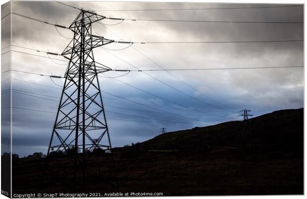 Electricity pylons in a field on a cloudy day in w Canvas Print by SnapT Photography