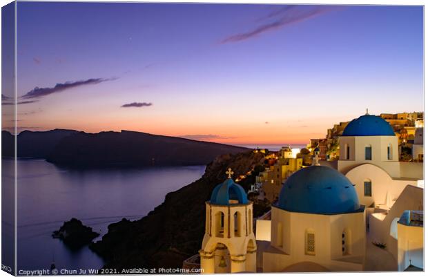 Blue domed churches and traditional white houses facing Aegean Sea with warm sunset light in Oia, Santorini, Greece Canvas Print by Chun Ju Wu
