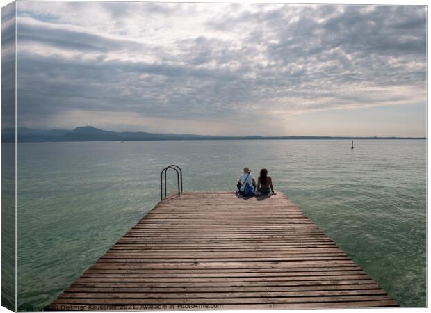 Tourists Sitting on jetty on Lake Garda in Sirmione Canvas Print by Dietmar Rauscher