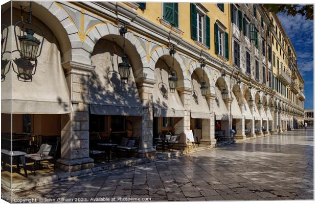 The Spianada is one of the largest plazas in Greece, the most interesting and lively square is the Liston, the building of arcades full of lively cafes. Canvas Print by John Gilham