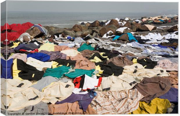 Freshly laundered clothes and fabrics drying on rocks by the sea at Mumbai, India Canvas Print by Gordon Dixon