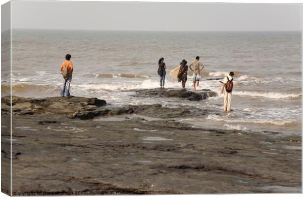 Group of Indian students stand on rocks at Mumbai as the tide comes in Canvas Print by Gordon Dixon