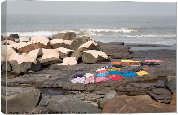 Freshly laundered clothes and fabrics drying on rocks by the sea at Mumbai, India Canvas Print by Gordon Dixon