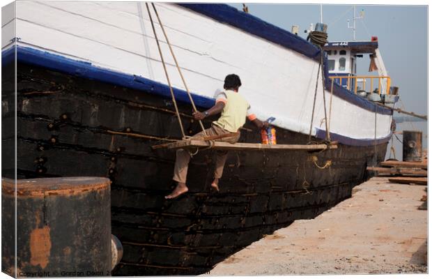 A ship repairer paints an old wooden ship in Mangalore, India Canvas Print by Gordon Dixon