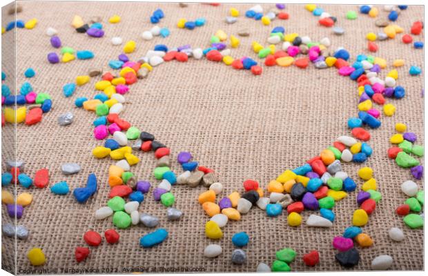 Colorful pebbles form a heart shape on canvas grou Canvas Print by Turgay Koca
