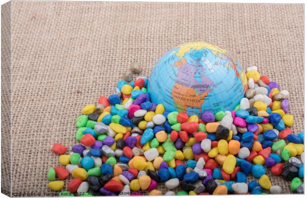 Little model globe amid colorful pebbles  Canvas Print by Turgay Koca