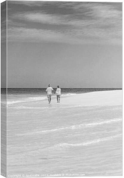 Mature couple walking on beach by ocean Bahamas Canvas Print by Spotmatik 