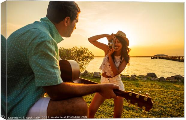 Smiling female taking photograph of partner playing guitar Canvas Print by Spotmatik 