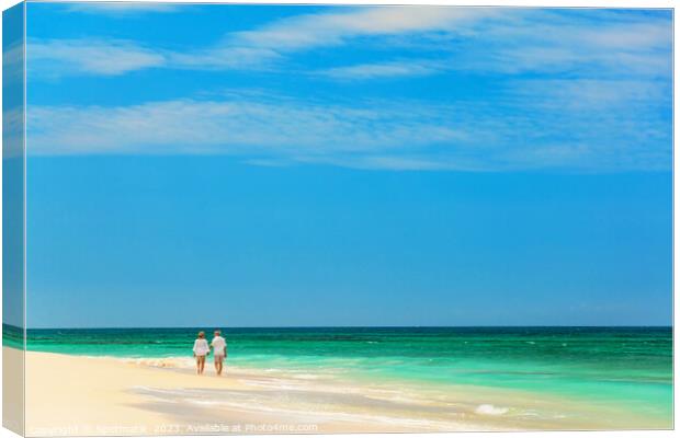 Mature couple walking along shoreline at beach resort Canvas Print by Spotmatik 