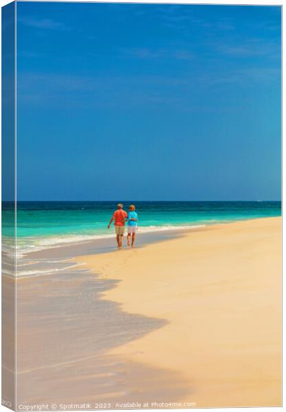 Tropical island shoreline with retired couple walking barefoot Canvas Print by Spotmatik 