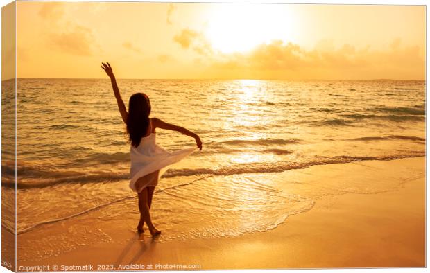 Asian girl standing in ocean waves at sunrise Canvas Print by Spotmatik 