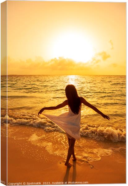 Asian girl standing in ocean waves at sunrise Canvas Print by Spotmatik 