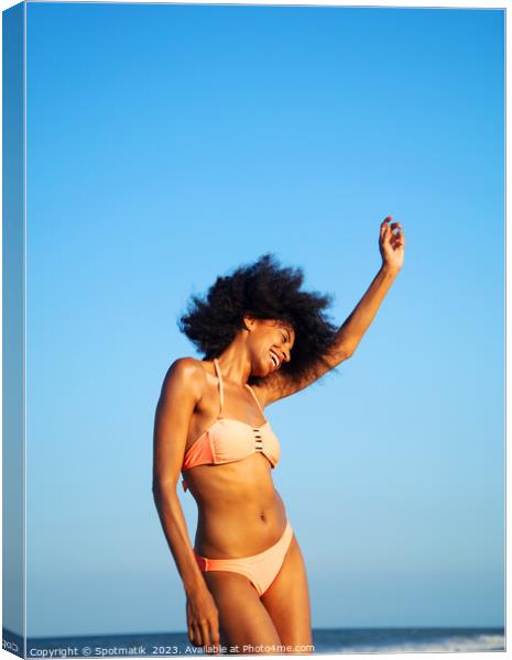 Afro girl in swimwear dancing on the beach Canvas Print by Spotmatik 