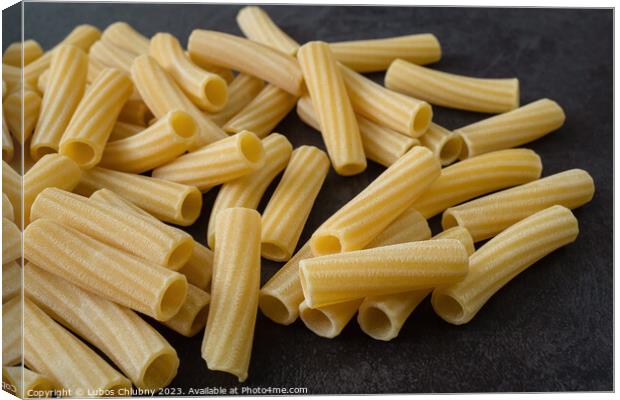 Raw italian penne rigate pasta isolated on black background Canvas Print by Lubos Chlubny