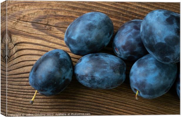 Ripe plums on a wooden table Canvas Print by Lubos Chlubny