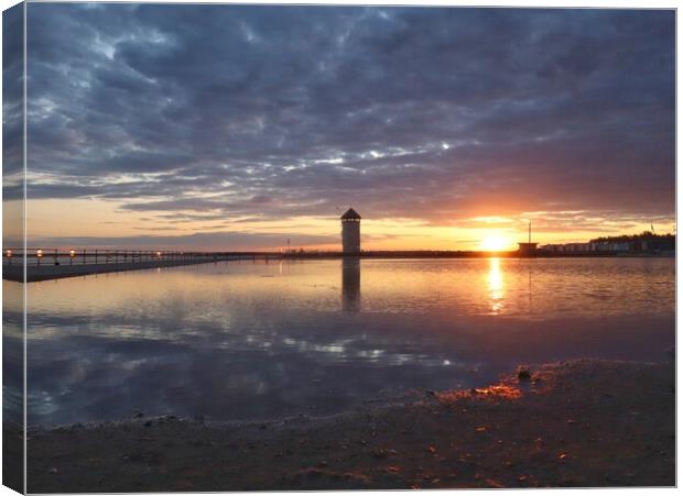 Sun setting over Batemans Tower in Brightlingsea in full reflections  Canvas Print by Tony lopez