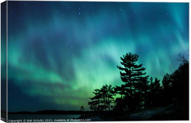 Northern lights erupt over a lake in Minnesota in a dark sky ove Canvas Print by Rob Schultz